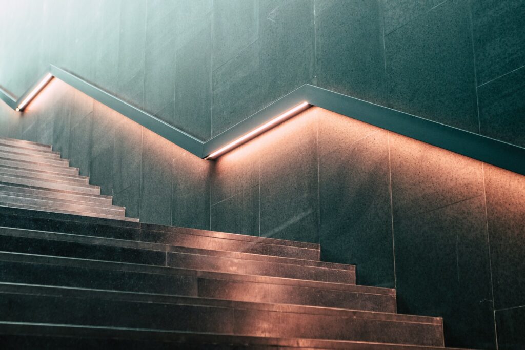 An image of a staircase with moody lighting under the handrails.