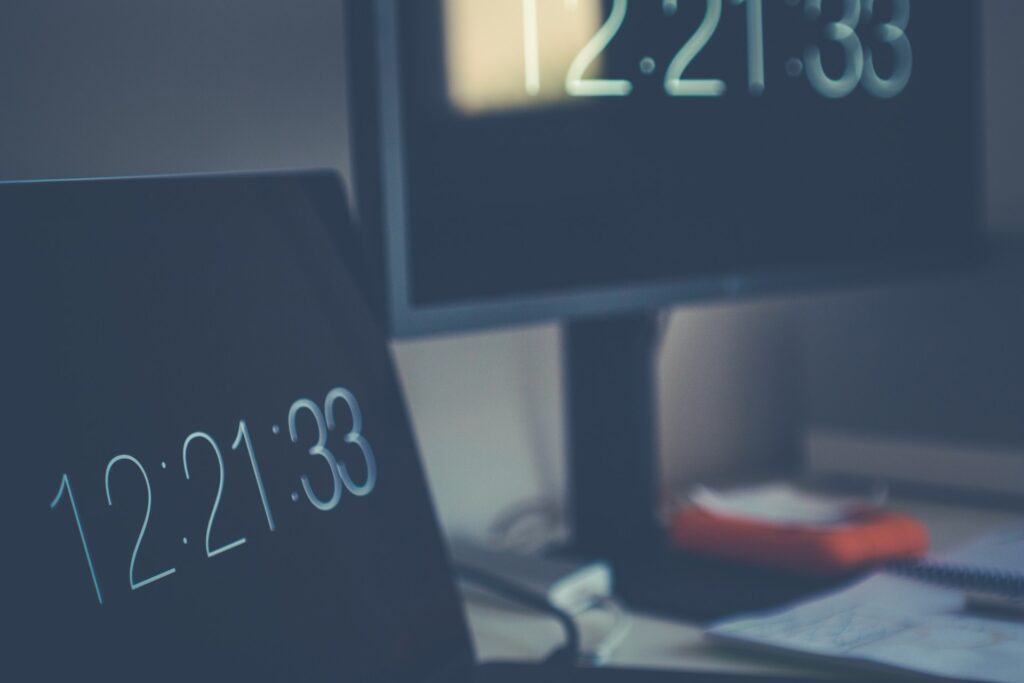 A slightly blurred image of two computer monitor's displaying the time. 